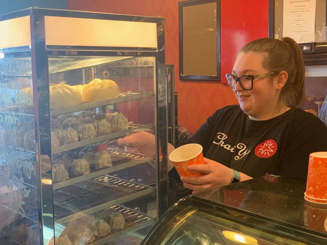 Chai-Yo team member holding a freshly made coffee behind the counter