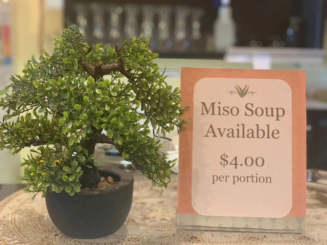 Miso soup sign beside a small bonsai tree on the café counter